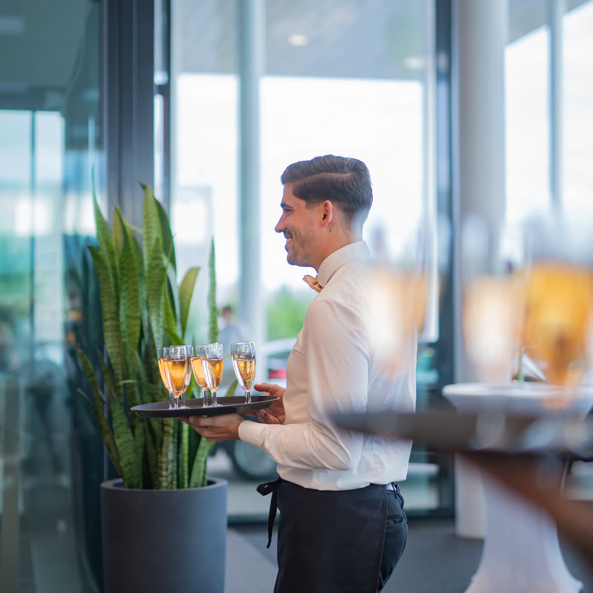 Servicekraft trägt Champagner-Gläser bei einem Event